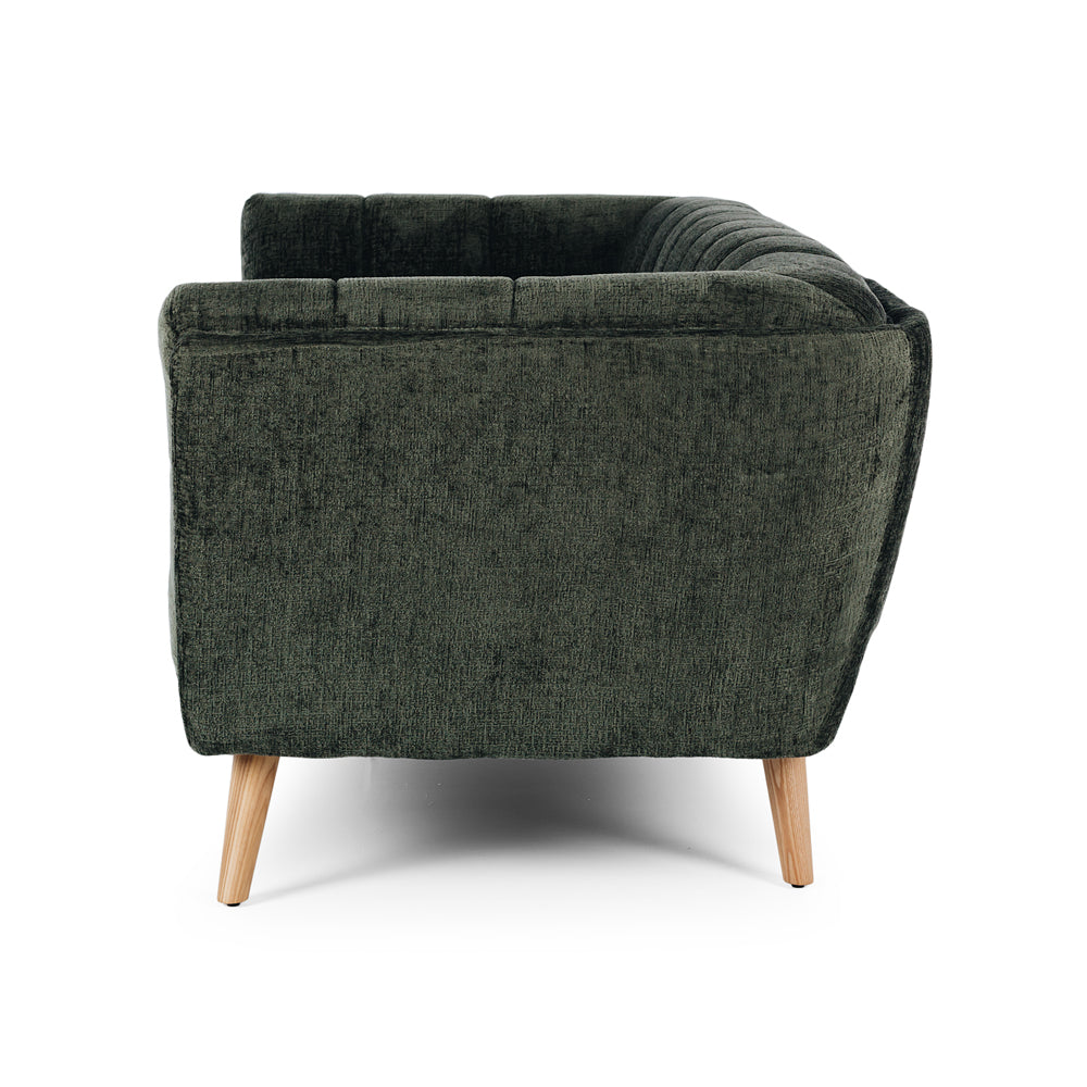 Side profile of the Towelie Sofa in Fern Green, highlighting its low profile, curved silhouette and channel-tufted upholstery.